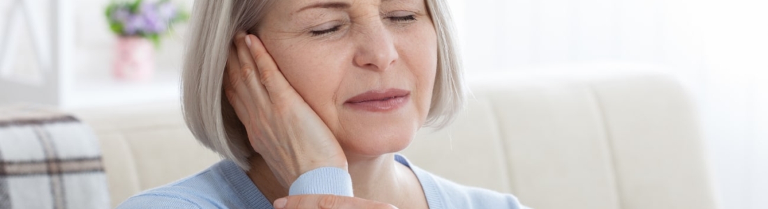 Mulher segurando a têmpora devido à neuralgia do trigêmeo