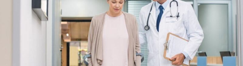 Doctor walking with patient while holding clipboard