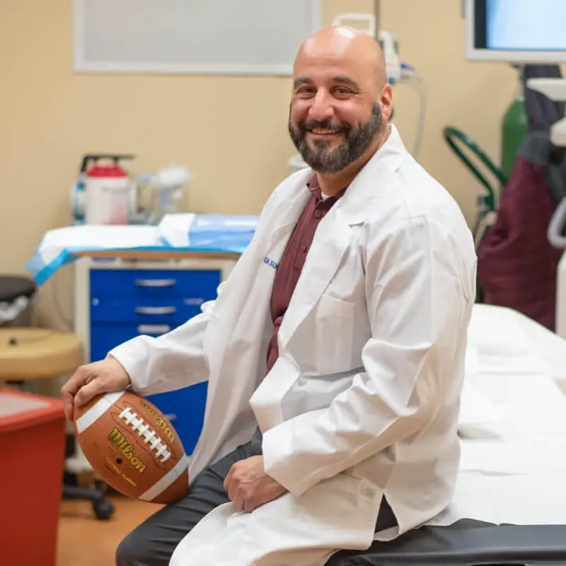 El Dr. Ventrudo, del NYSI, sostiene un balón de fútbol