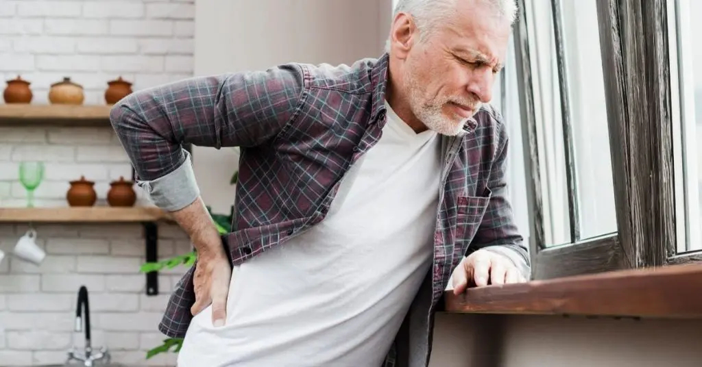 Man leaning against while while holding back in pain