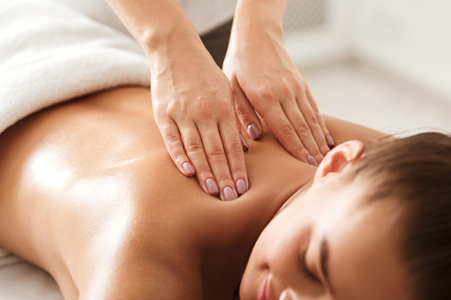 Mujer joven recibiendo un masaje en el cuello por parte de un terapeuta