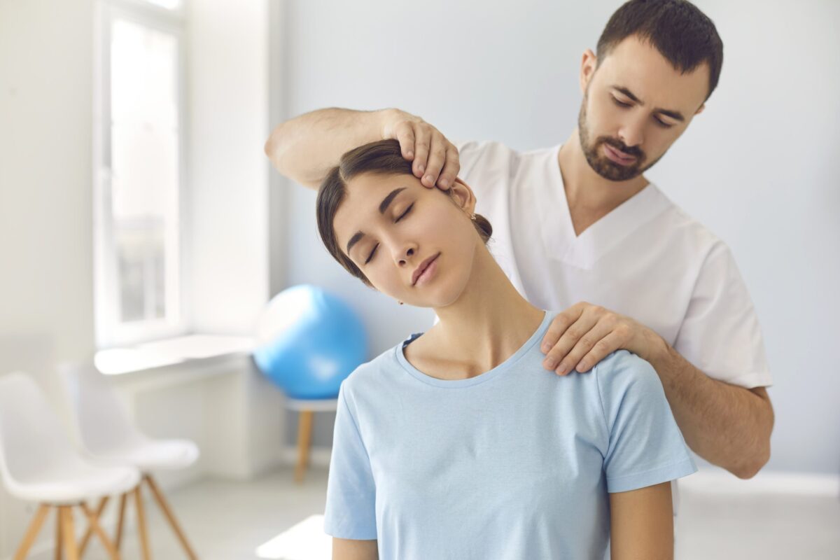 Physical therapist helping female patient stretch neck