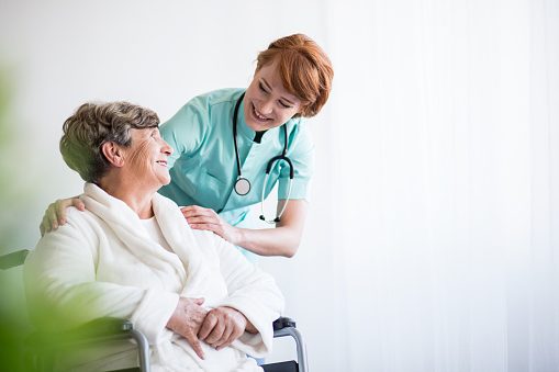 Médico sonriendo con paciente en silla de ruedas