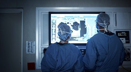 Dos cirujanos analizan los escáneres médicos de un paciente y arrojan luz sobre el diagnóstico durante la cirugía