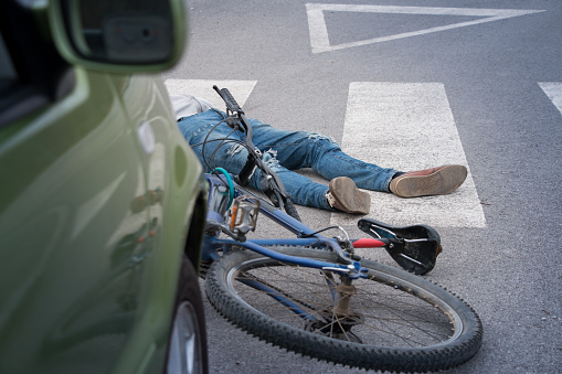Man on ground after bicycle accident involving a car