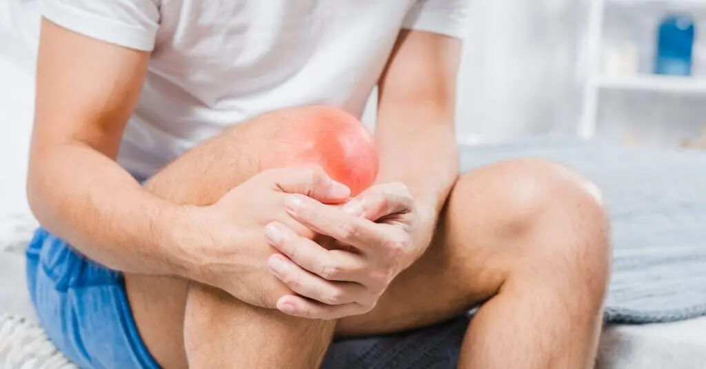 Man grasping his right knee while in pain