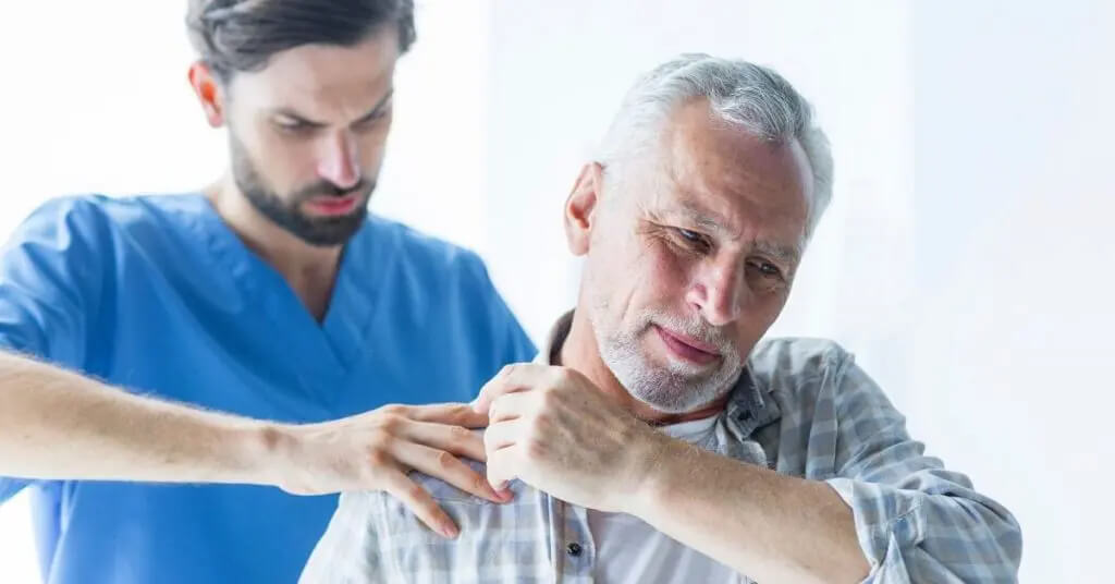 Man pointing to shoulder while doctor diagnoses