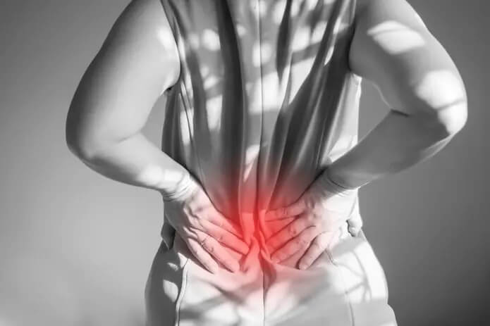 Image of woman holding lower back in pain