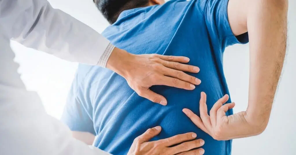 Hombre señalando a la espalda mientras el médico examina la zona