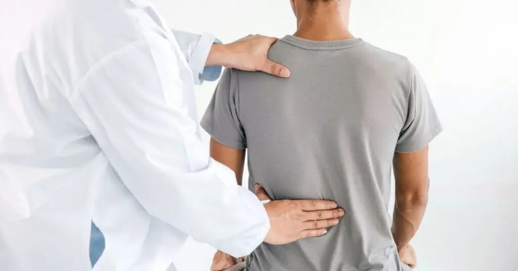 Médico de la columna vertebral examinando la espalda de un paciente