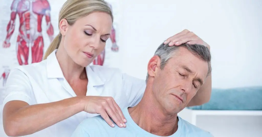 Doctor helping stretch man's neck