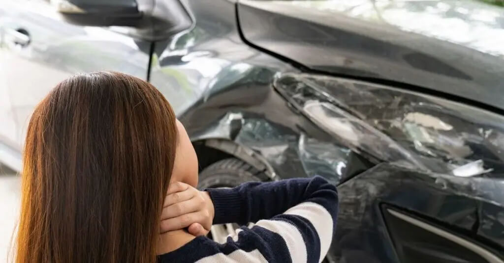 Une femme se tient le cou après un accident de voiture