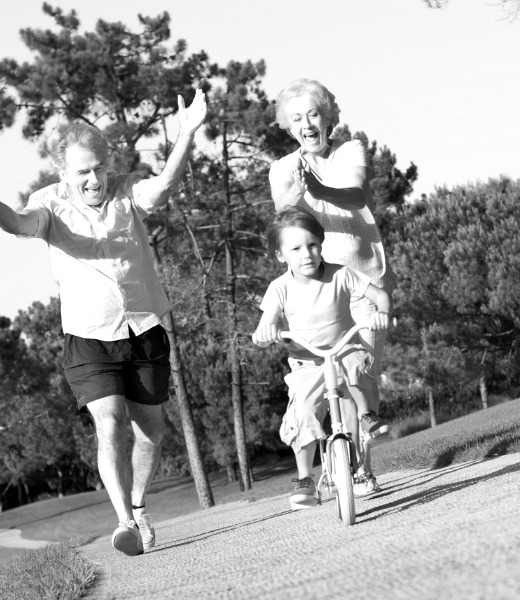 Elderly couple teaching child how to ride a bike